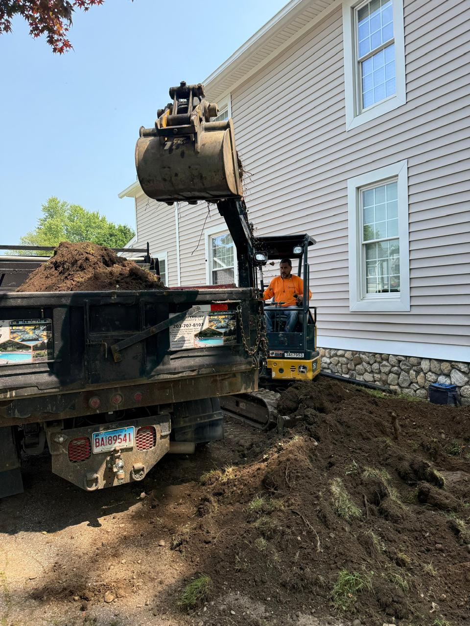 Excavation work for new masonry services foundation near residential home in Connecticut.