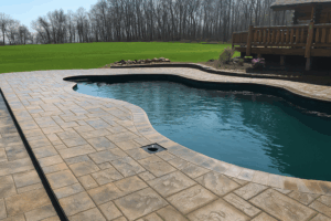 Custom poolside patio built with stamped concrete, crafted through expert masonry services.