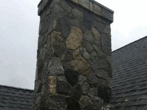 Stone chimney showcasing expert masonry solutions on a residential rooftop.