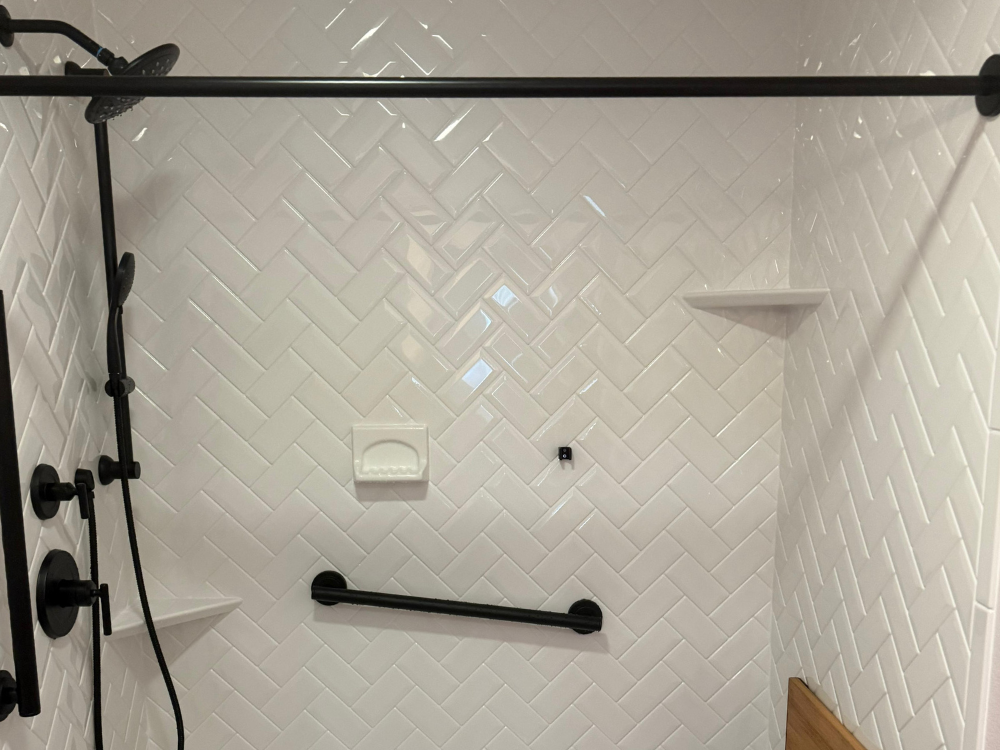 Shower with white herringbone tile pattern illustrating interior masonry solutions.