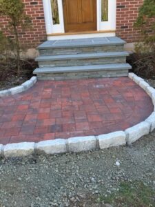 Front entrance featuring a red paver landing with granite edging after walkway installation