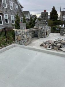 Early-stage stone outdoor kitchen installation with block core and natural-stone facing.