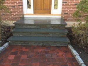 Close-up of stone steps and red paver entrance showing detailed masonry work