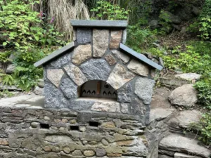 Custom stone outdoor fireplace built into natural landscape with precision masonry and stone detailing