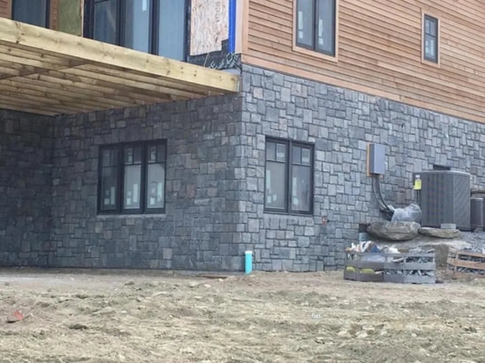 Custom stone veneer installation on residential foundation with precise window detailing