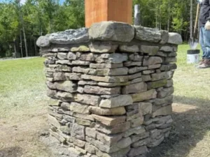 Stone column light post installation showing stacked natural stone base under timber post
