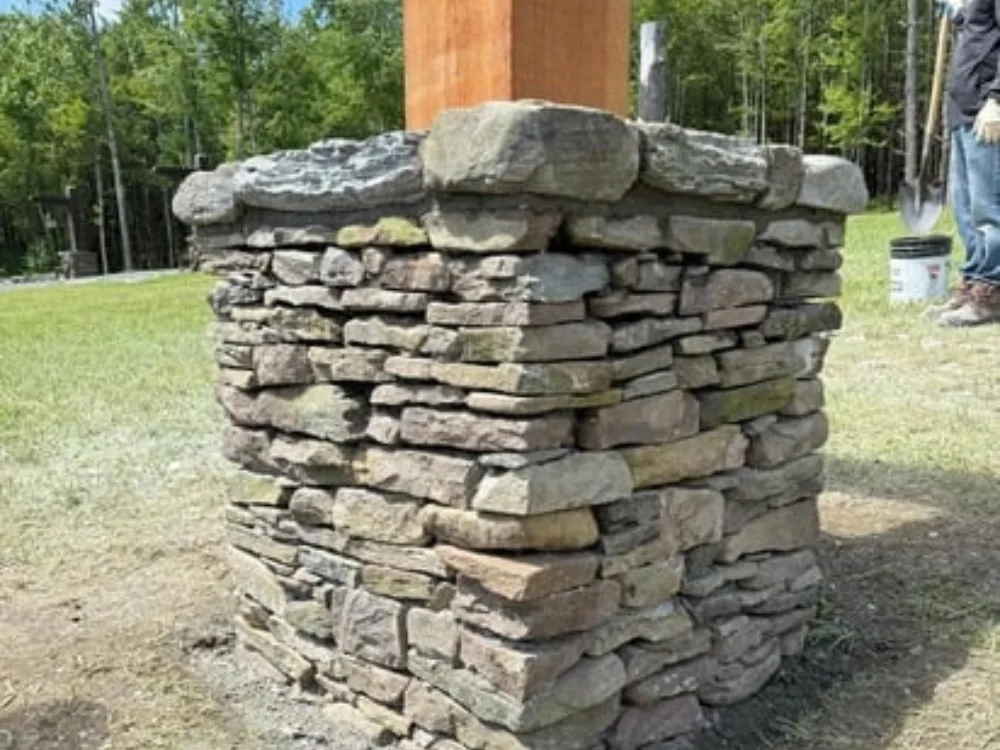 Stone column light post installation showing stacked natural stone base under timber post